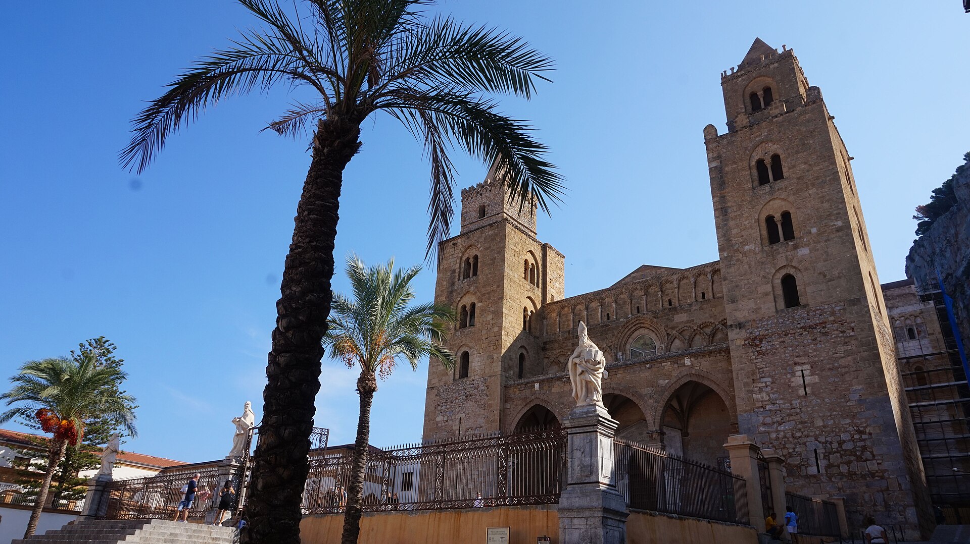 Il duomo normanno di Cefalu con le sue due torri, incorniciato da palme sotto la Rocca